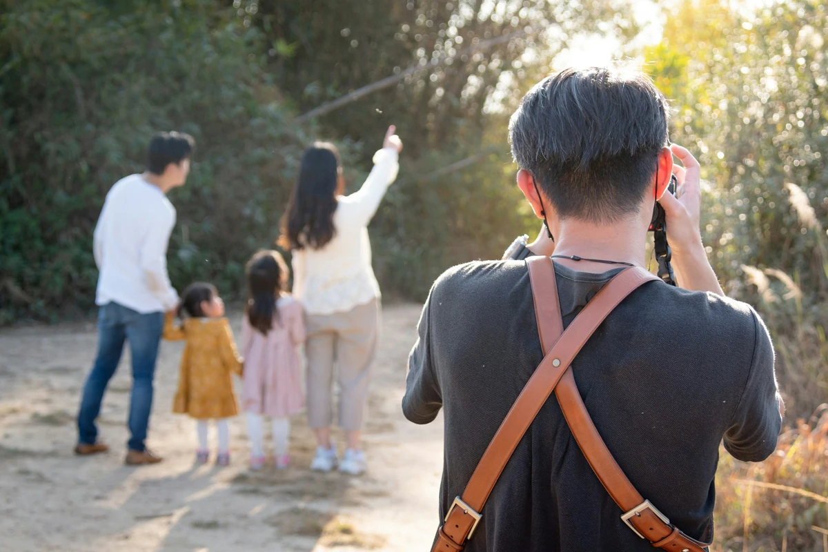 Fotografer memotret keluarga di taman; foto stok