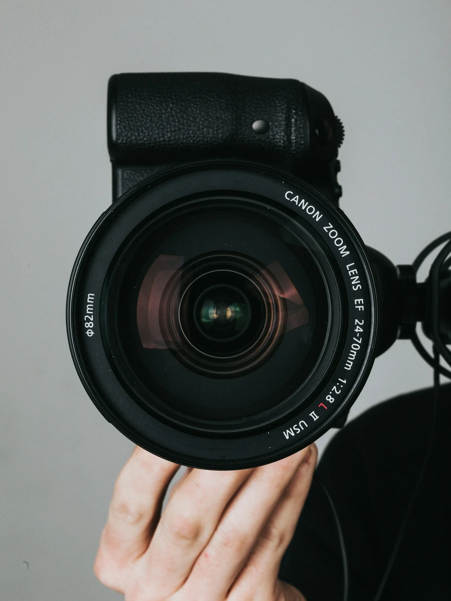 Tangan memegang kamera dengan lensa besar; foto stok